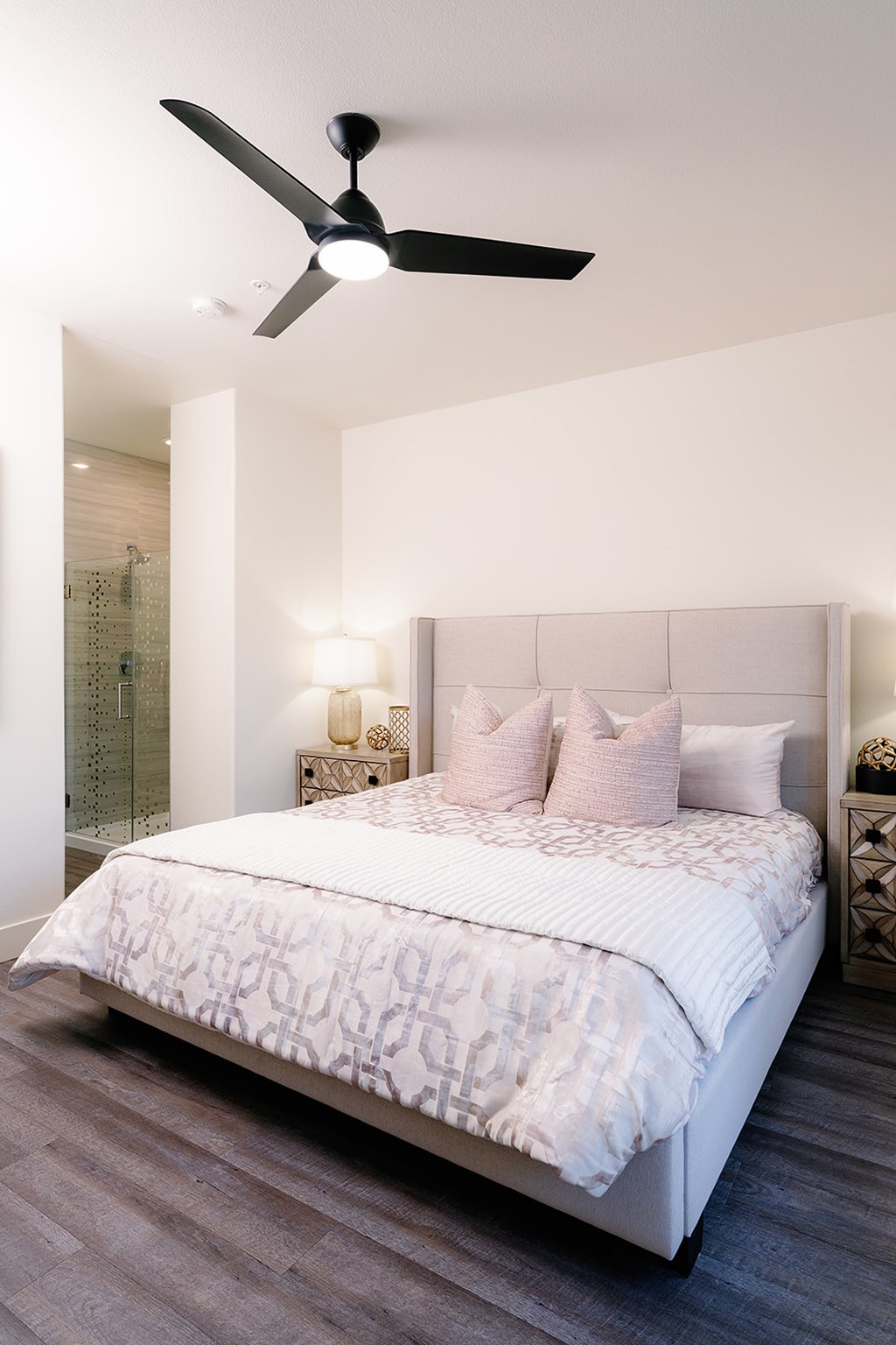 A bedroom with a large bed and a ceiling fan.