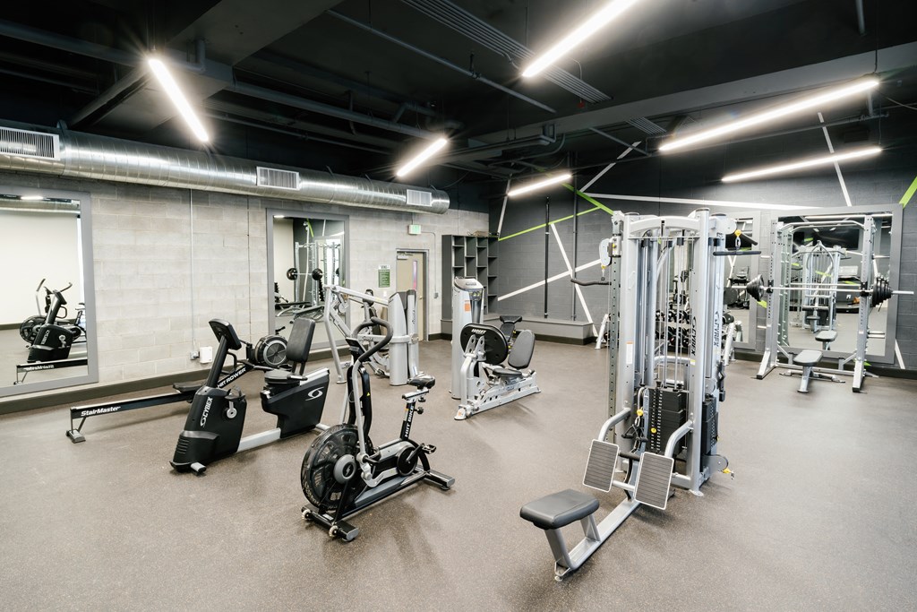 a spacious fitness center with cardio equipment and weights
