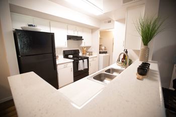 a kitchen with white cabinets and black appliances and a sink at Austin Crest Apartments, Reno, Nevada