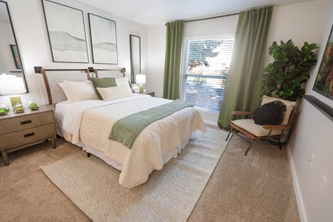 A bedroom with a large bed and a chair.