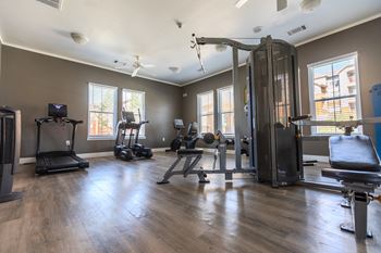 a gym with exercise equipment and windows in a home with wood floors at Austin Crest Apartments, Reno