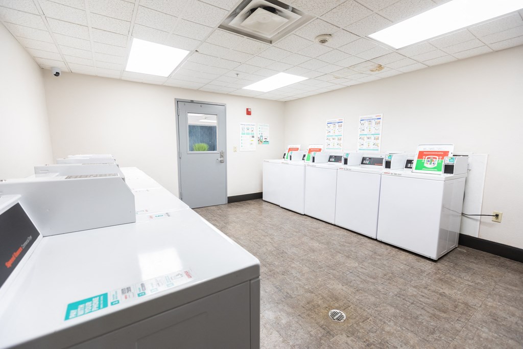 a laundry room with washers and dryers and a door to a hallway at ParcOne60, Reno, 89501