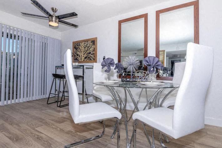 a dining room with a glass table and white chairs at Evoq Apartment Homes, Las Vegas, 89169  