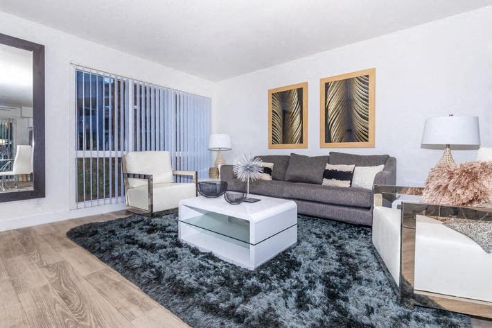 a living room with white furniture and a blue rug at Evoq Apartment Homes, Las Vegas  