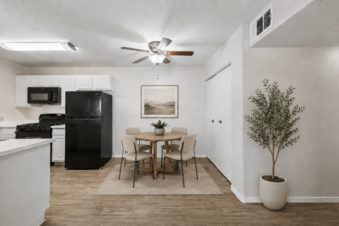 A kitchen with a black refrigerator and a dining table with chairs.