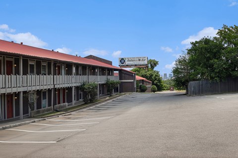 an empty parking lot in front of a white building with a red roof