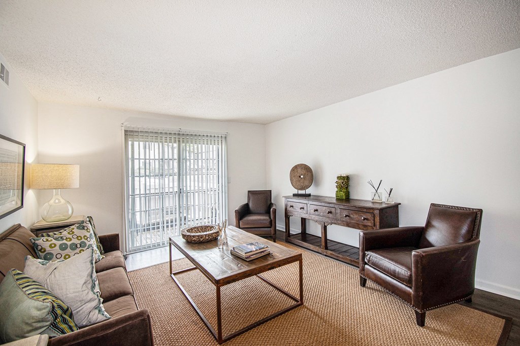 A living room with a brown couch, a brown chair, a coffee table, and a lamp.