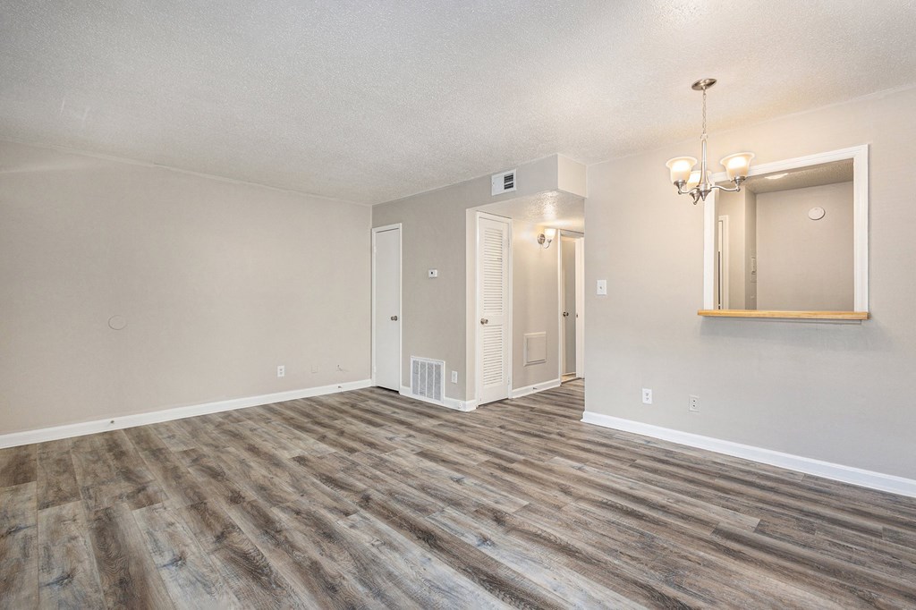 an empty living room with wood flooring and white walls