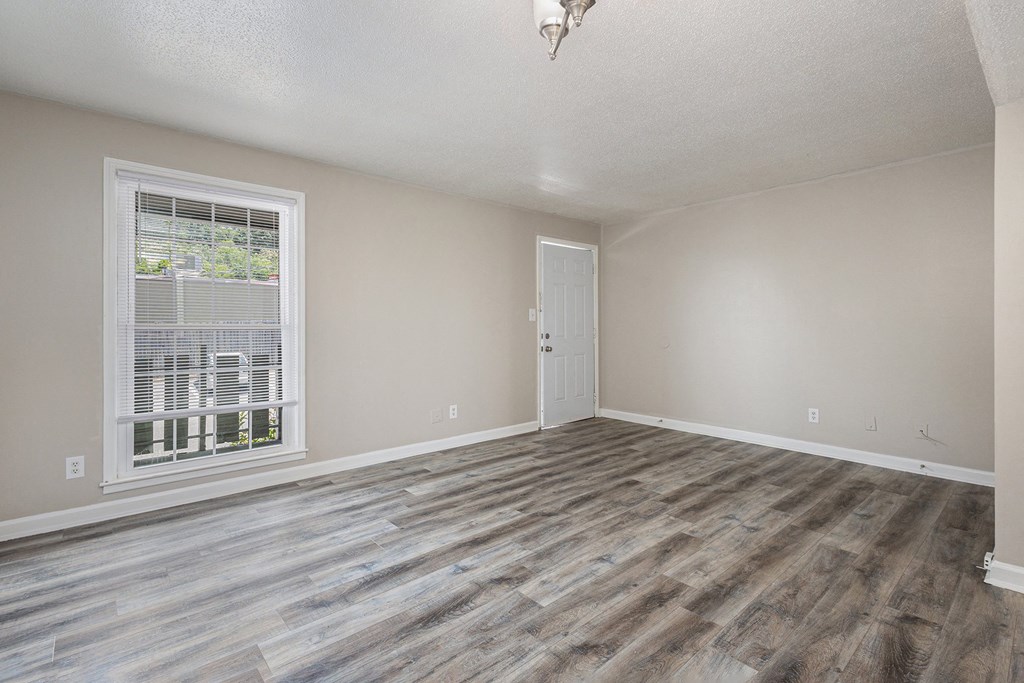 an empty living room with wood flooring and a window
