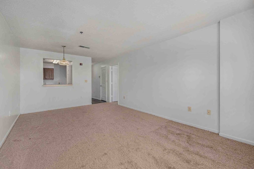 an empty living room with white walls and carpet
