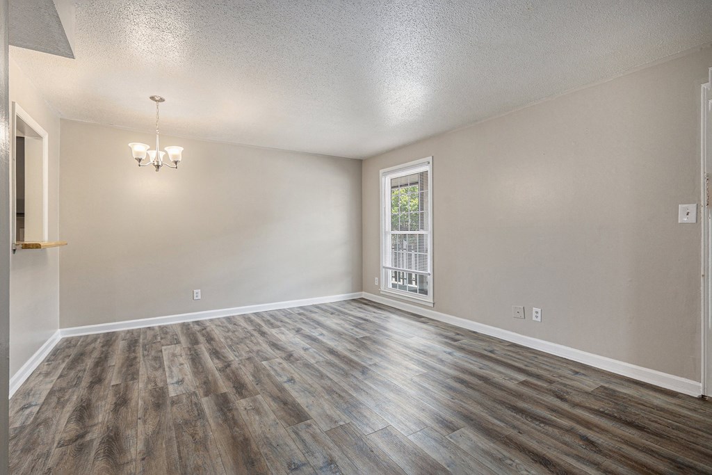 an empty living room with wood flooring and a window