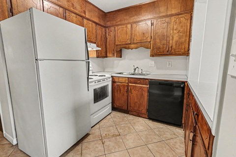 A kitchen with a white refrigerator and wooden cabinets.