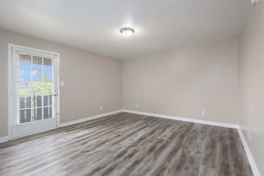 an empty living room with wood flooring and a window