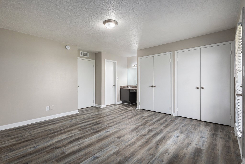 an empty living room with wood floors and white closets