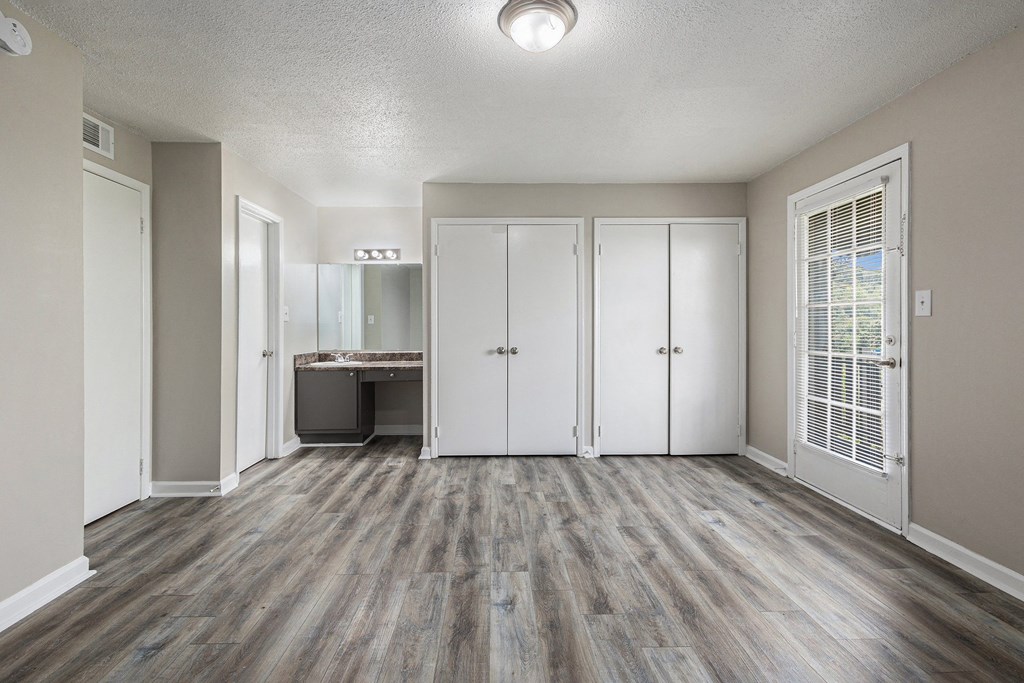 an empty living room with white closets and a bathroom