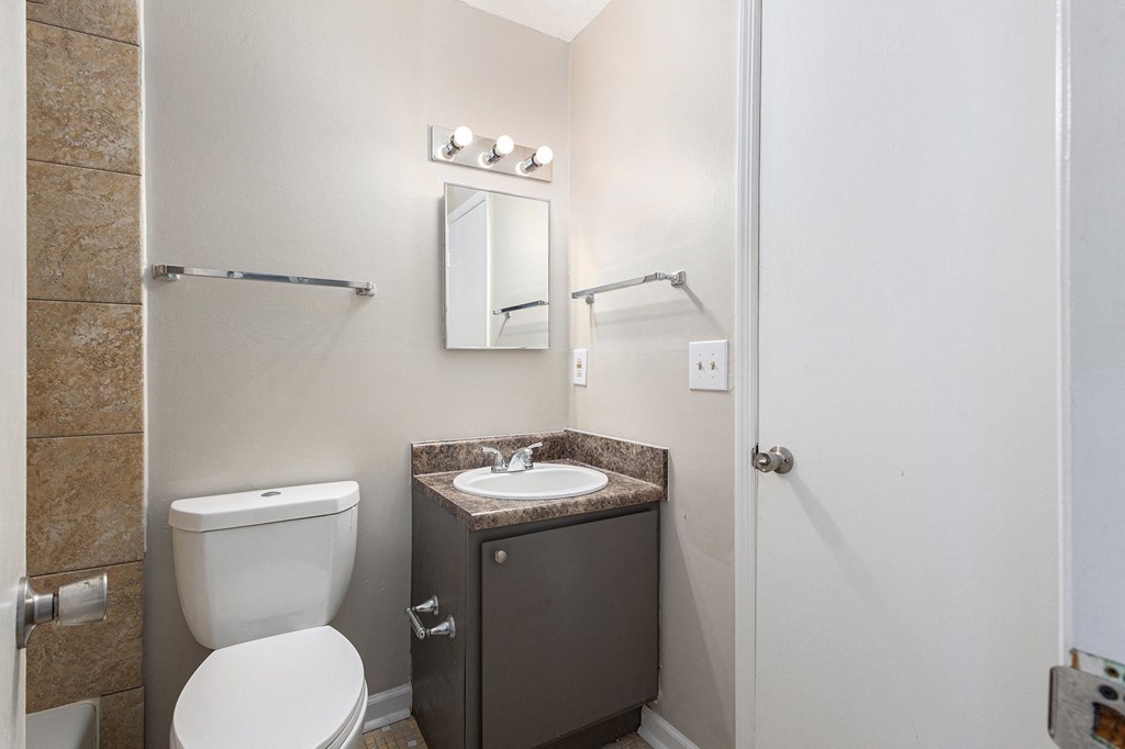 a bathroom with a toilet sink and mirror and a shower