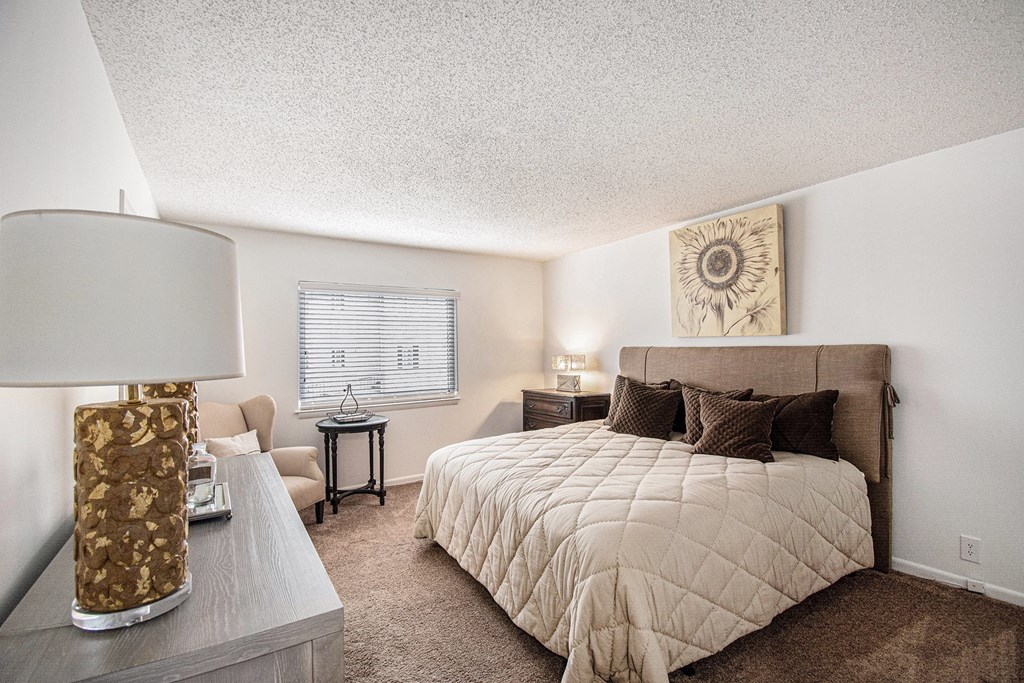 A bedroom with a large bed and a lamp on a side table.