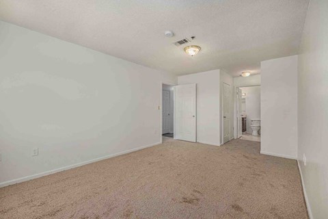 an empty bedroom with white walls and carpeted flooring