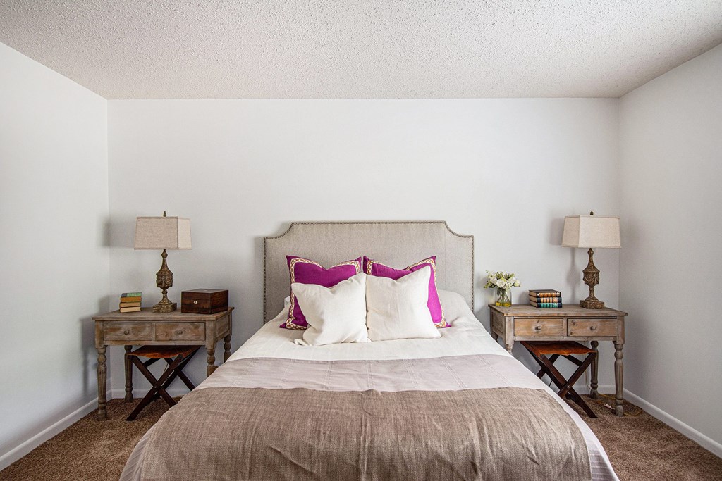 A bedroom with a bed, two nightstands, and a lamp.