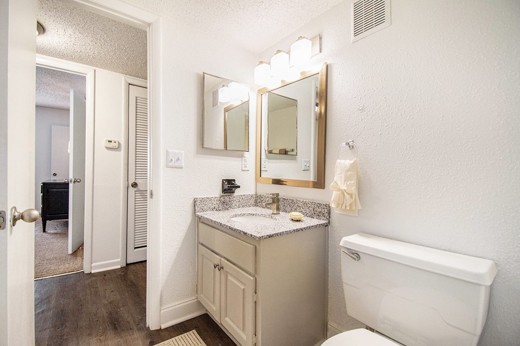 A bathroom with a white toilet, sink, and mirror.