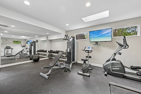 A spacious gym with a variety of equipment including treadmills, stationary bikes, and weight machines.