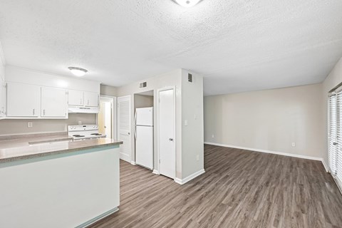 A kitchen with white cabinets and a wooden floor.