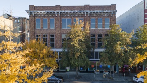 A black car is parked in front of a brick building.
