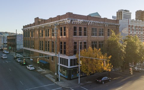 A large brick building with a green awning sits on a street corner.
