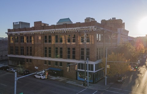 A large brick building with a green roof and a white car parked in front.