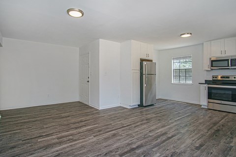 the living room of an apartment with a refrigerator and a stove