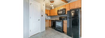 an empty kitchen with black appliances and wood cabinets
