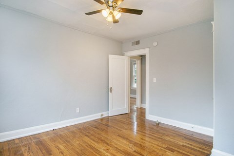 an empty living room with wood floors and a ceiling fan