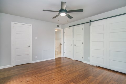 an empty living room with a ceiling fan and white doors