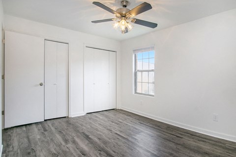 an empty living room with white walls and a ceiling fan