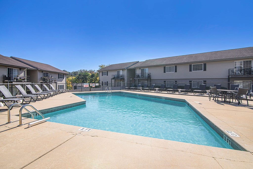 A swimming pool surrounded by lounge chairs and buildings.