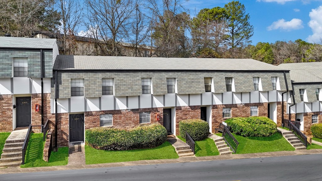 A row of houses with a green lawn in front.
