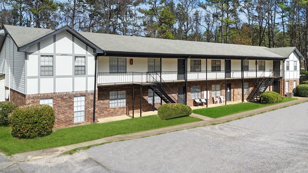 A white and black building with a grey roof and a green lawn in front.