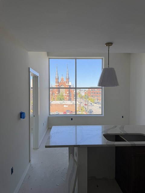 A room with a table and a view of a church through a window.
