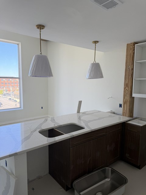 A kitchen under construction with a sink and two hanging lights.