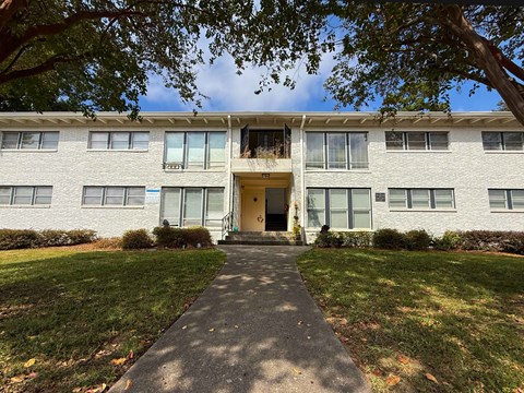 A white building with a yellow door and windows on the side.