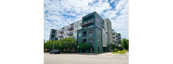 A modern apartment building with balconies and a car parked in front.