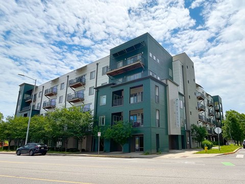A modern apartment building with balconies and a car parked in front.