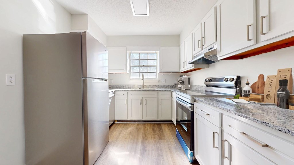 A kitchen with a refrigerator, oven, and cabinets.