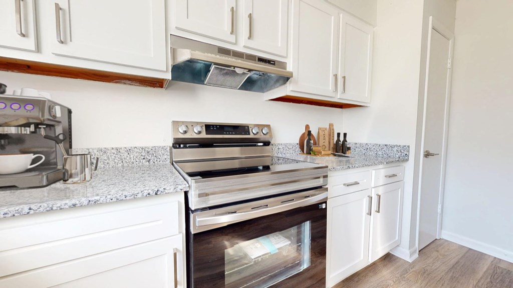 A kitchen with white cabinets and a granite countertop.
