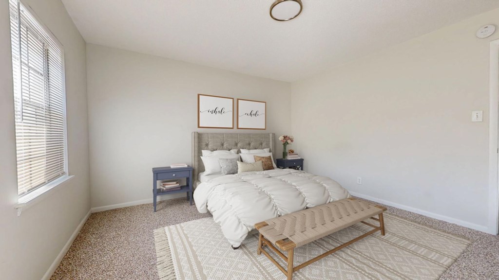 A bedroom with a bed, nightstands, and a bench.