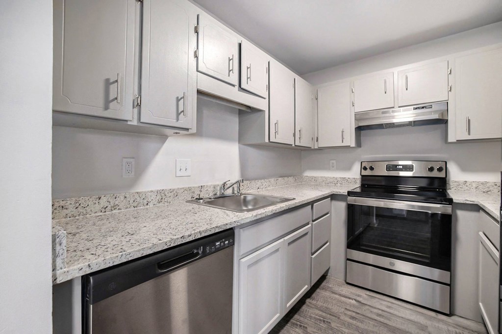 a kitchen with white cabinets and granite counter tops and stainless steel appliances