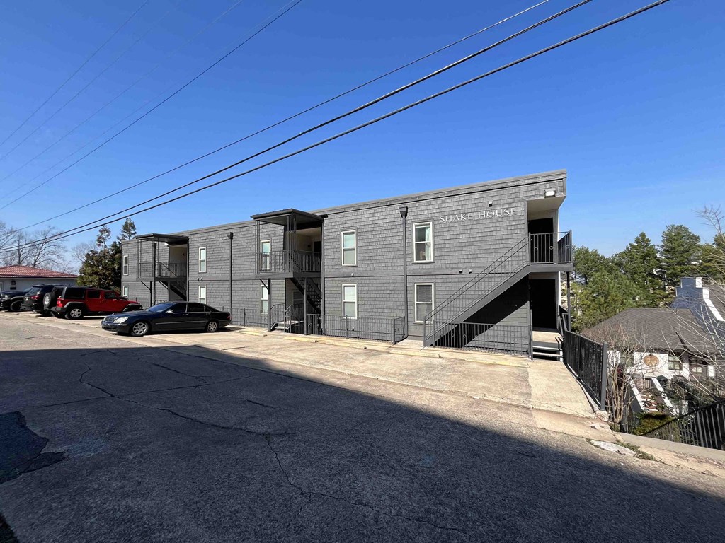 a grey apartment building with stairs and a parking lot