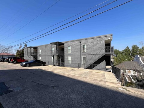 a grey apartment building with stairs and a parking lot