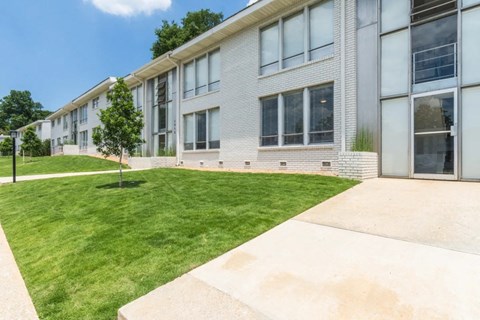 the front of a white building with a lawn and grass