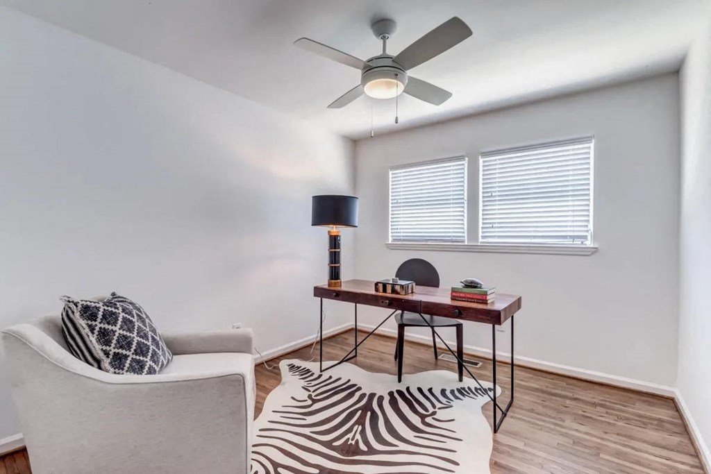 a living room with a couch and a desk with a ceiling fan